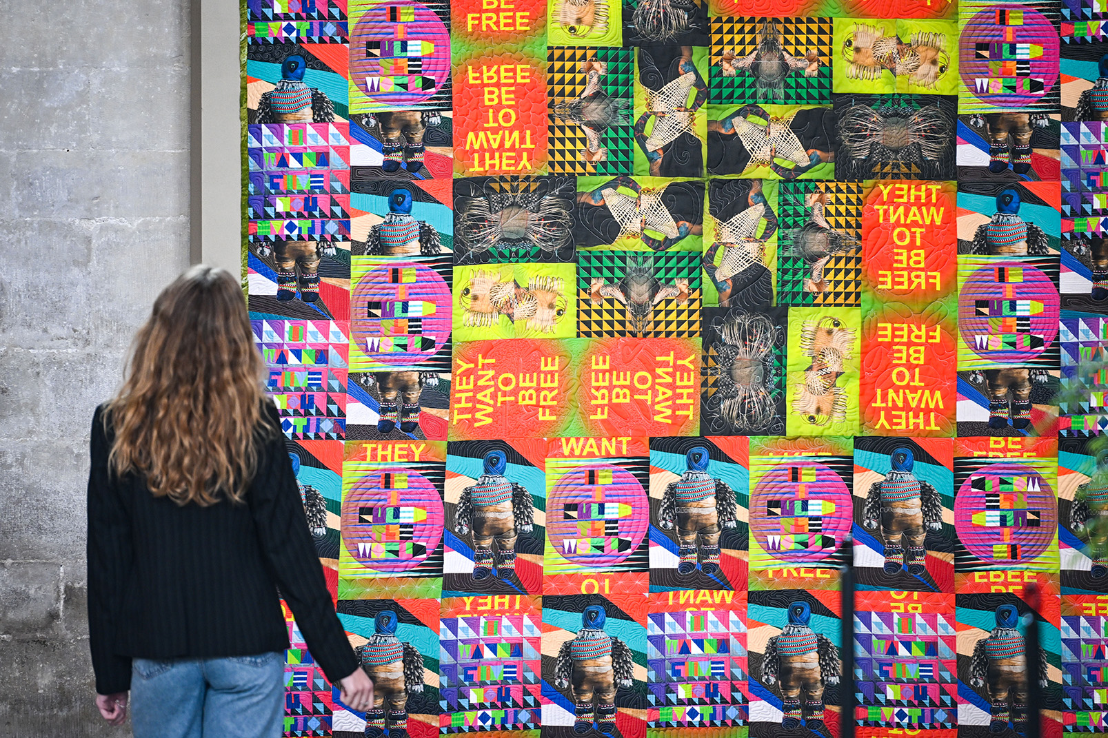 Woman looking at a colourful quilt that is hung inside Salisbury Cathedral