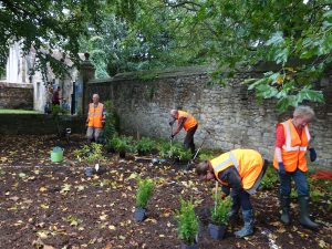 A number of volunteers in high viz jackets are hard at work on the flowerbed. 