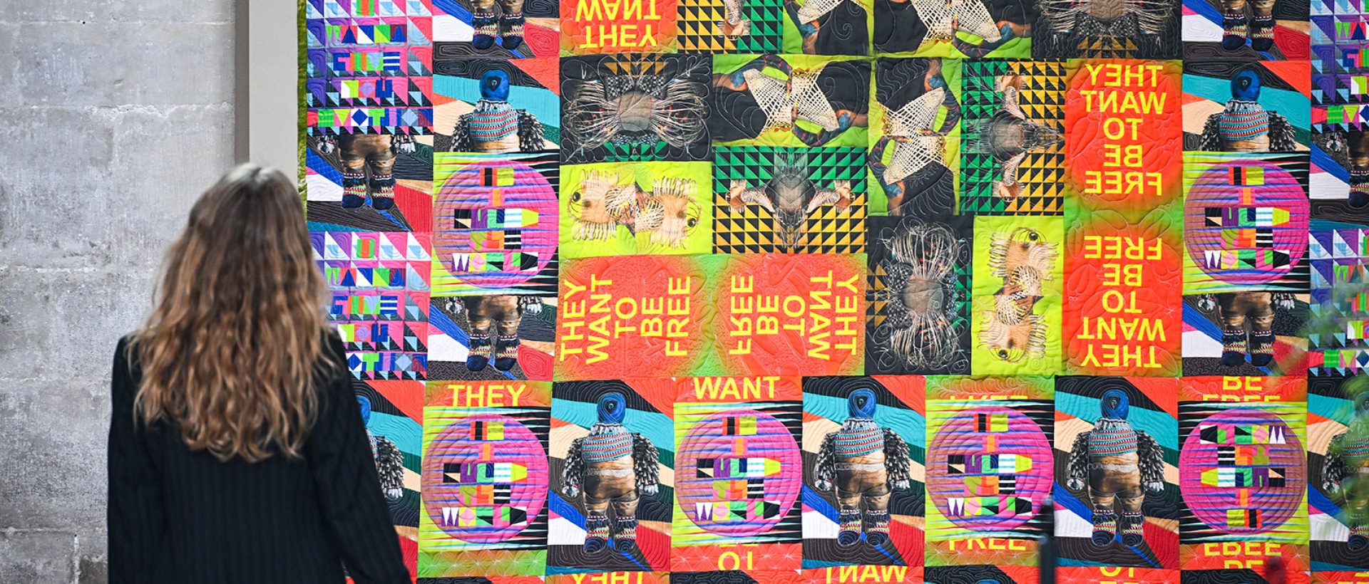 Woman looking at a colourful quilt that is hung inside Salisbury Cathedral