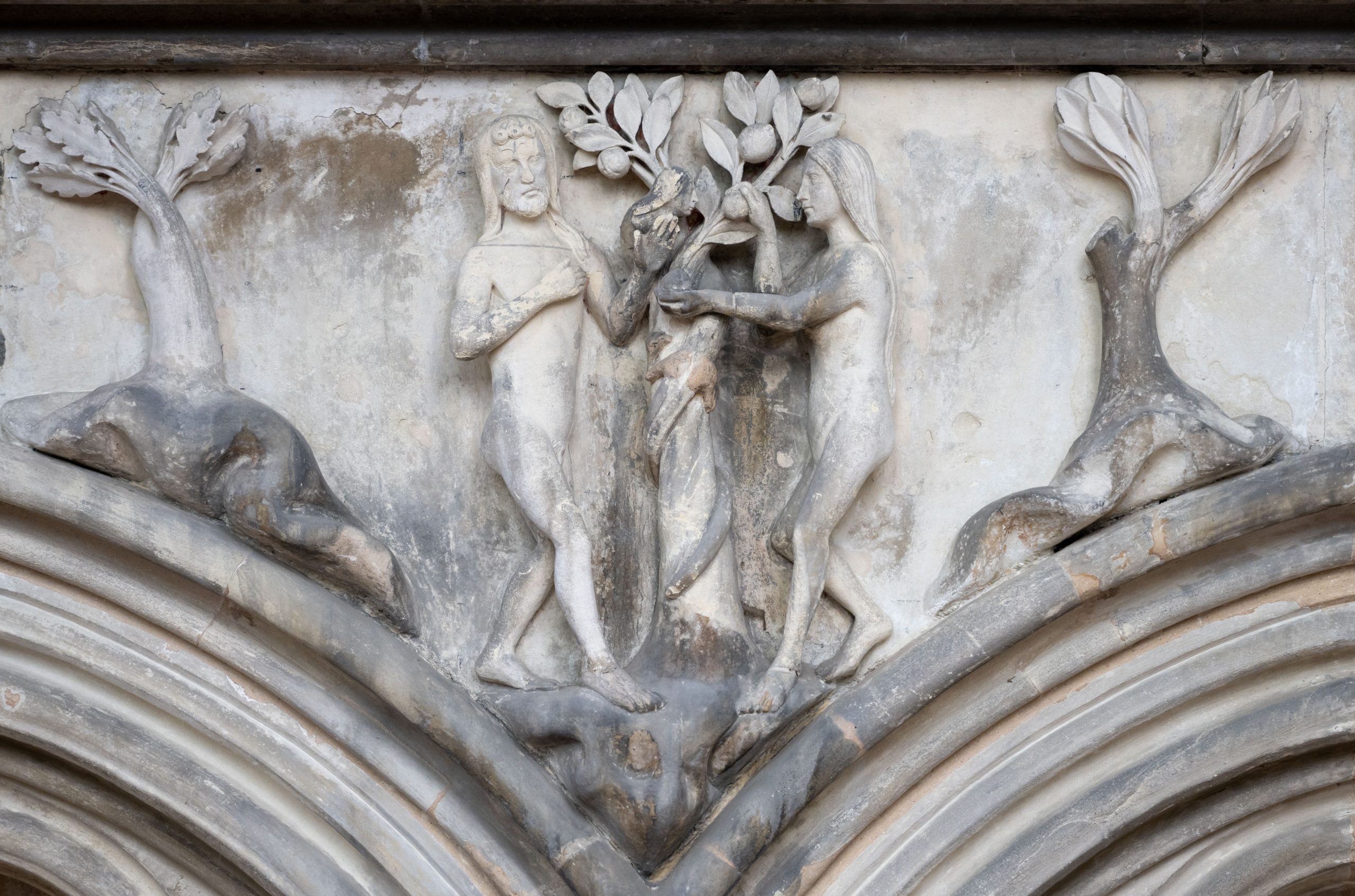 Photos shows detail of carved stone frieze focussed on Adam and Eve and the tree of knowledge.