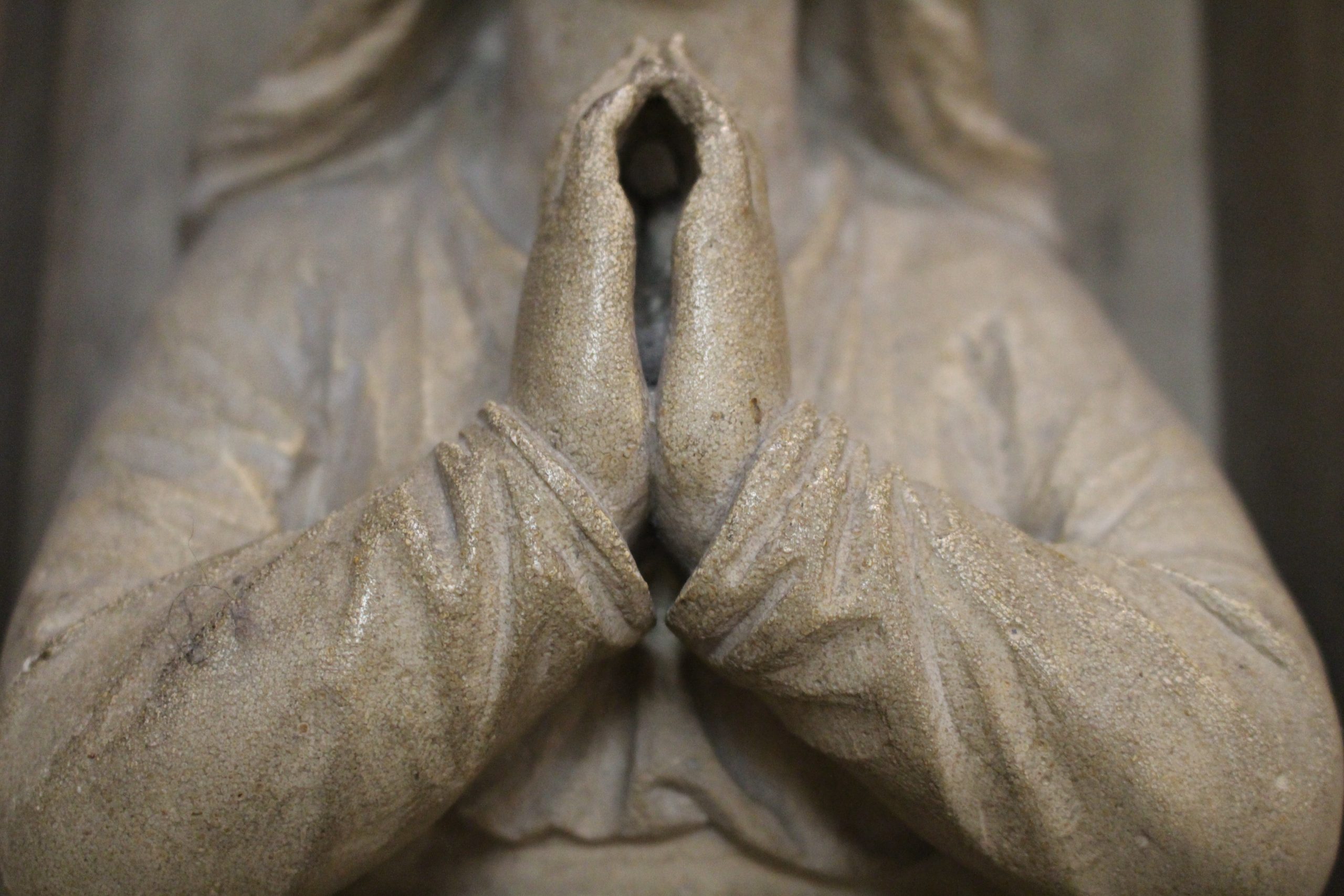 Detail of stone statue with hands shown in praying gesture
