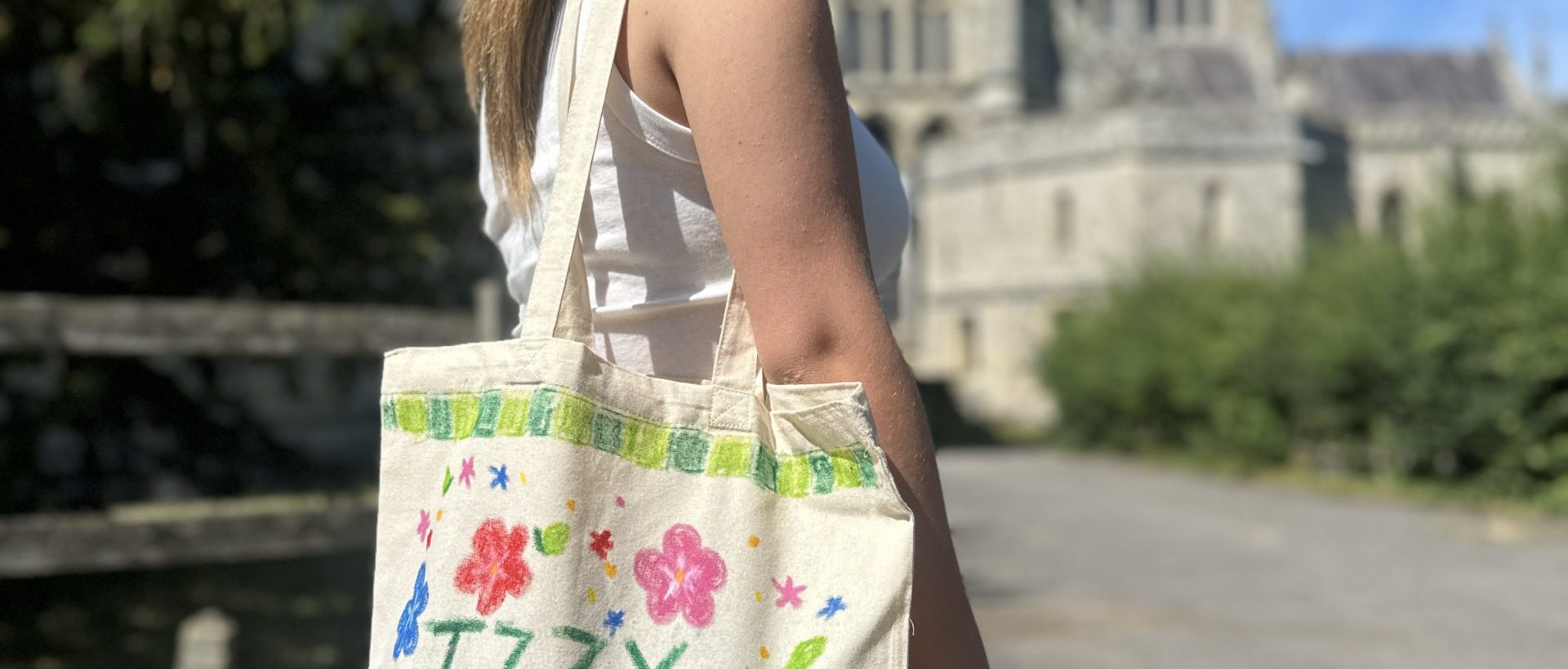Photo shows girl wearing a tote bag on her shoulder which has been painted with bright colours