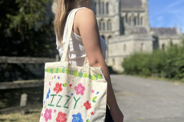 Photo shows girl wearing a tote bag on her shoulder which has been painted with bright colours
